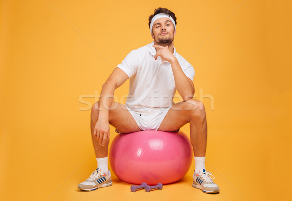 Handsome young sportsman sitting on the fitness ball Stock photo © deandrobot
