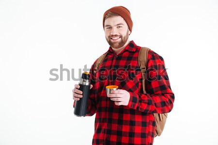 Smiling hipster man holding thermos Stock photo © deandrobot