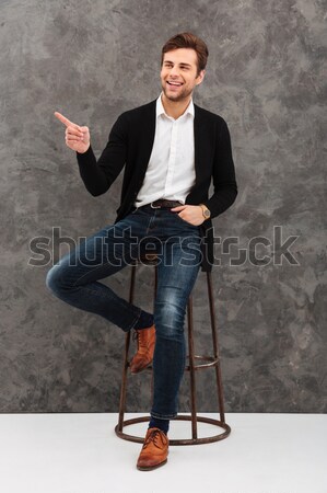 Casual man in plaid shirt standing and pointing away o Stock photo © deandrobot