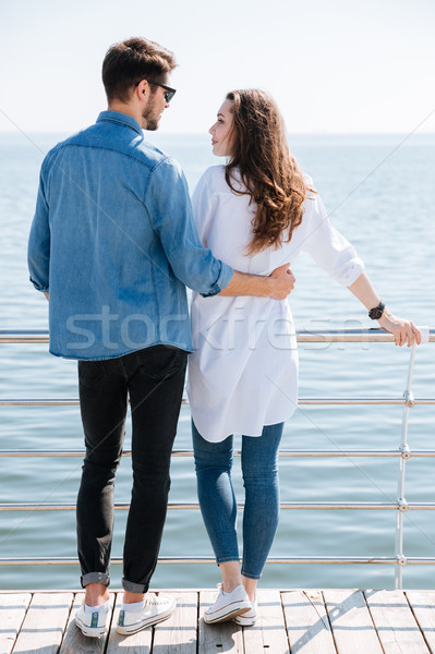 Full length of a young couple standing backwards hugging Stock photo © deandrobot
