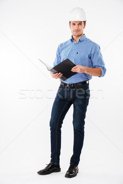 Confident man building engineer in hard hat writing in folder Stock photo © deandrobot