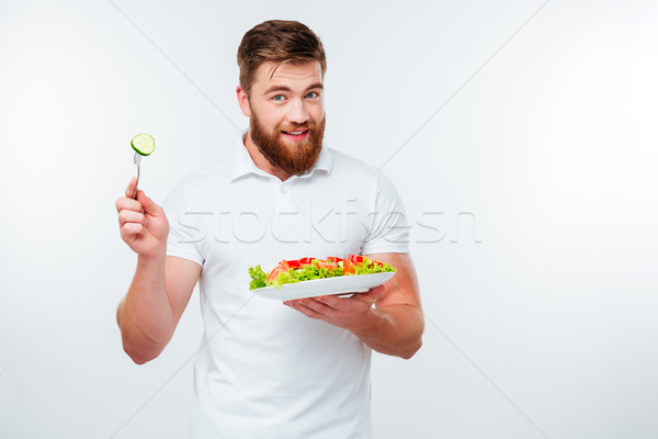 Young man holding fork to eat fresh vegetable salad meal Stock photo © deandrobot