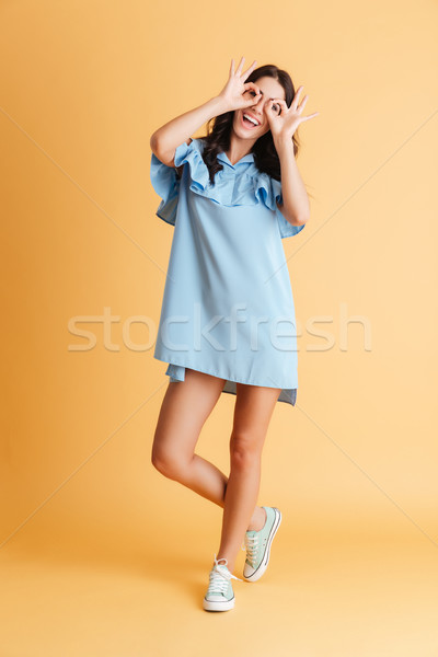 Cheerful young woman looking at camera through fingers Stock photo © deandrobot