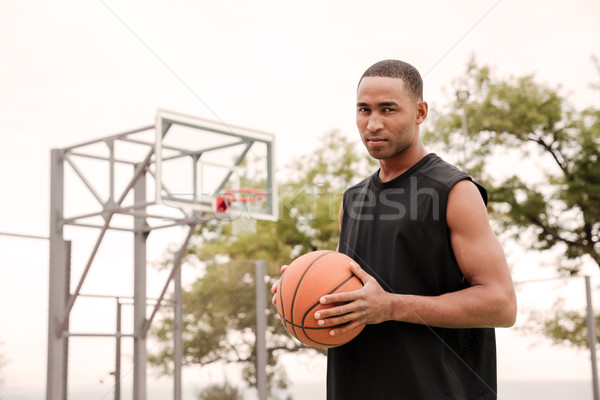 Attractive african serious basketball player standing in the str Stock photo © deandrobot