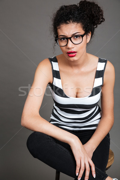 Serious african american young woman in glasses sitting on chair Stock photo © deandrobot