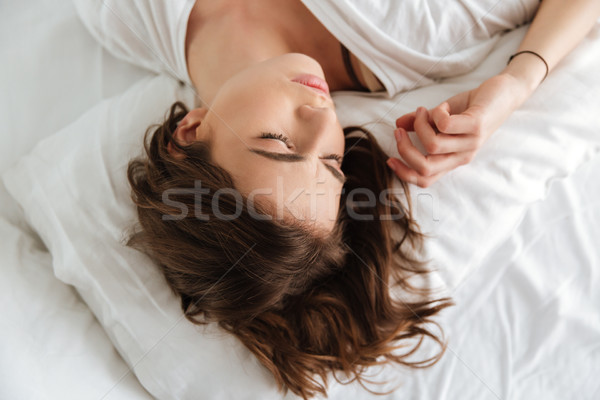 Tired pretty young woman sleeping on pillow in bed Stock photo © deandrobot