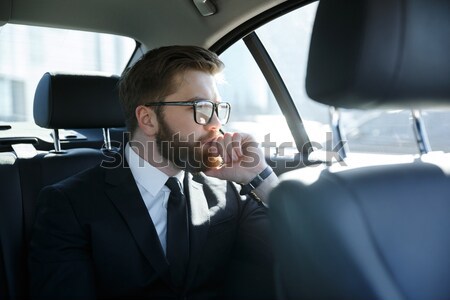 Concentrated young businessman analyzing documents while traveling Stock photo © deandrobot