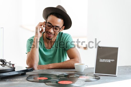 Smiling African man in t-shirt using record-player Stock photo © deandrobot