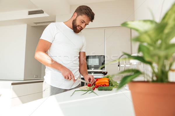 Side view of casual bearded man cuts vegetables Stock photo © deandrobot