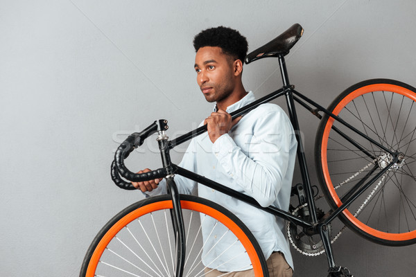 Young afro american man carrying bicycle Stock photo © deandrobot