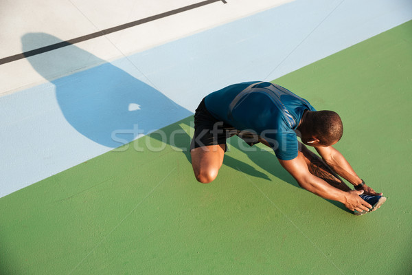 Top view portrait of a young african sportsman doing stretching Stock photo © deandrobot