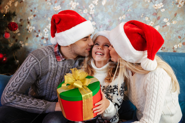Young father and mother in Santa's hat kissing those little daug Stock photo © deandrobot