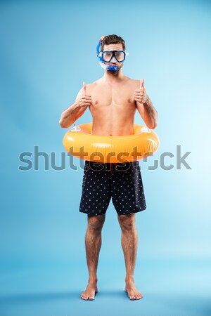 Cheerful young man standing with rubber ring Stock photo © deandrobot