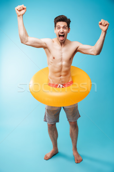 Full length portrait of a cheerful young shirtless man Stock photo © deandrobot