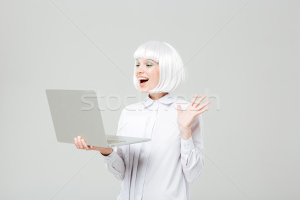 Cheerful lovely young woman standing and using laptop Stock photo © deandrobot