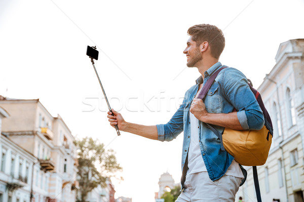 Tourist with backpack making selfies isolated on beautiful modern buildings Stock photo © deandrobot