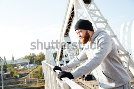 Tired young sports man in hat getting ready for jogging Stock photo © deandrobot