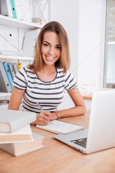 Cute female student with laptop and books working in university Stock photo © deandrobot