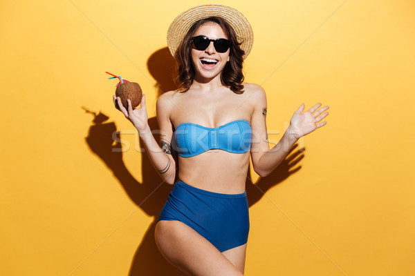 Smiling young lady in swimwear holding cocktail. Stock photo © deandrobot
