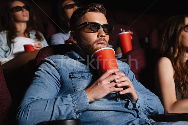 Concentrated young man sitting in cinema watch film Stock photo © deandrobot