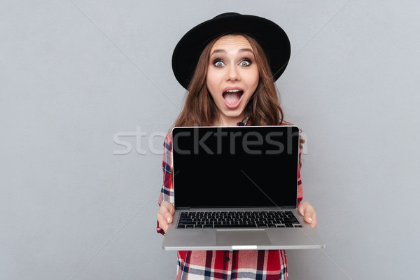 Excited casual girl in plaid shirt holding blank screen laptop Stock photo © deandrobot