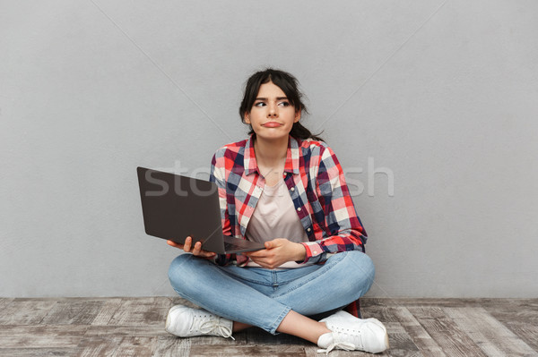 Sad displeased young lady student using laptop computer. Stock photo © deandrobot