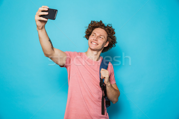 Stock photo: Photo of handsome college guy with curly hair wearing casual clo