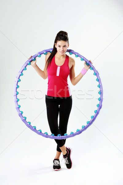 Young beautiful sport woman holding a massage hoop on gray background Stock photo © deandrobot