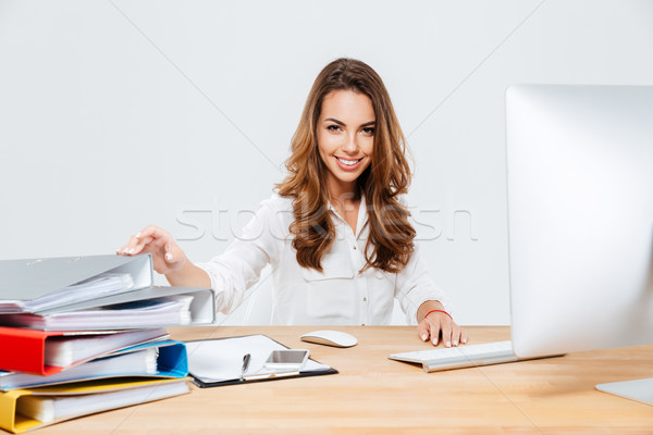 Smiling cheerful businesswoman sitting at her working place Stock photo © deandrobot