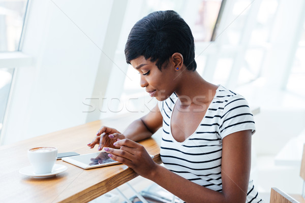 Attractive african businesswoman using tablet amd having coffee break Stock photo © deandrobot