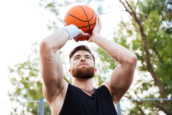 Portrait of a handsome man in sports wear playing basketball Stock photo © deandrobot