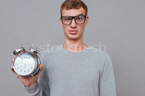 Young man in glasses showing clock Stock photo © deandrobot