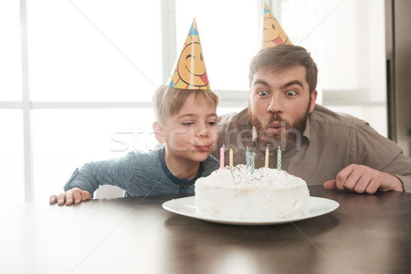 Handsome young father sitting near birtday cake with son. Stock photo © deandrobot