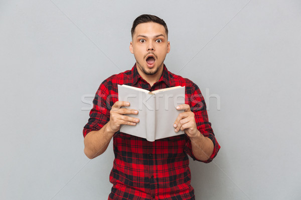 Shocked man holding book in hands Stock photo © deandrobot