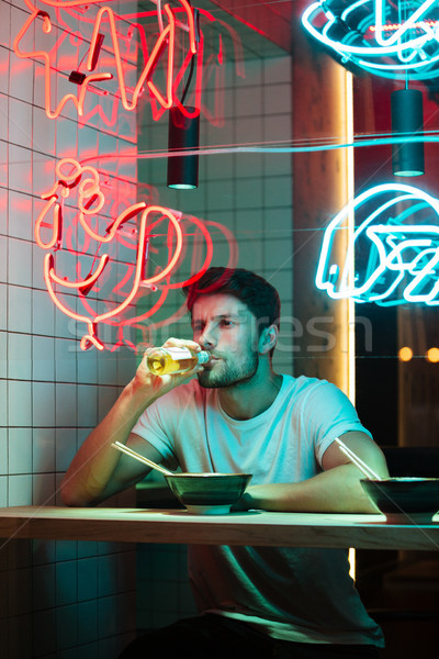 Handsome man sitting in cafe looking aside eating. Stock photo © deandrobot