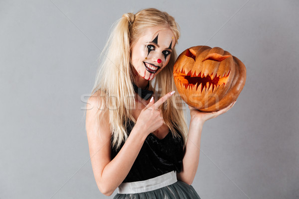 Smiling blonde woman in halloween make up holding carved pumpkin Stock photo © deandrobot