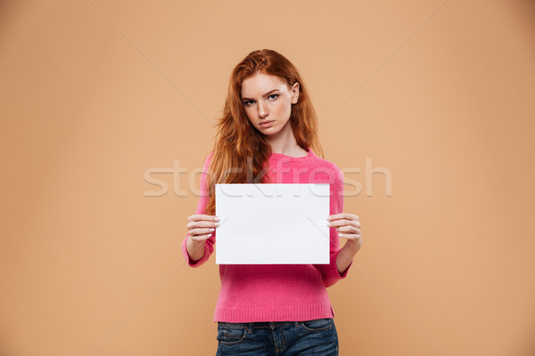 Portrait of an upset pretty redhead girl showing blank board Stock photo © deandrobot