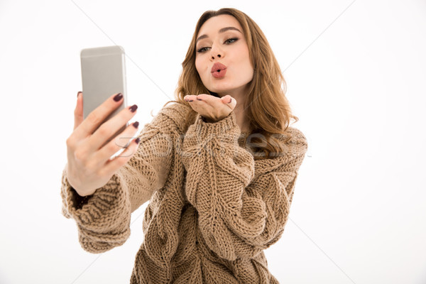 Lady dressed in sweater make selfie by phone blowing kisses. Stock photo © deandrobot