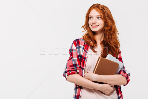 Pleased ginger woman in shirt holding books and looking away Stock photo © deandrobot