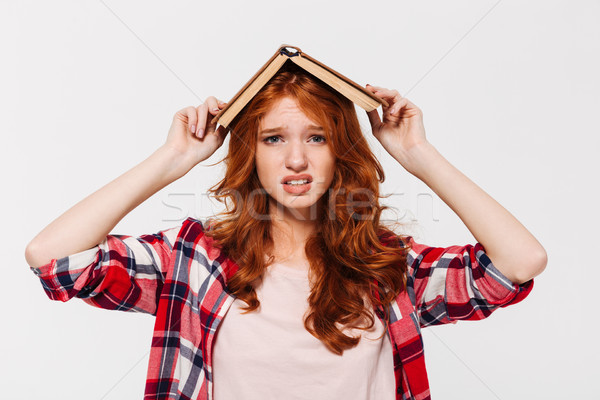 Confused ginger woman in shirt holding book on her head Stock photo © deandrobot