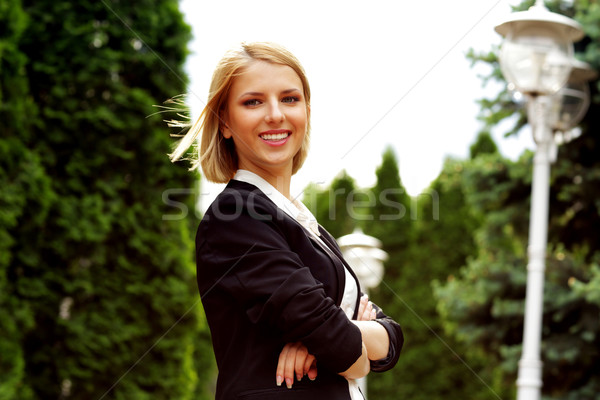 Portrait of a smiling attractive woman with arms folded in park Stock photo © deandrobot