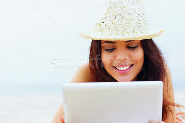 Young beautiful woman in swimming suit using her tablet on the beach Stock photo © deandrobot