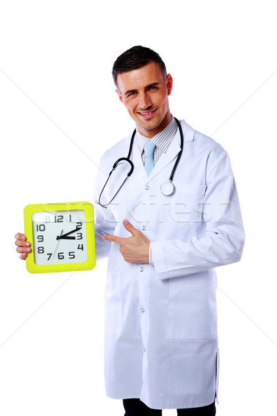 Portrait of a male doctor showing on clock over white background Stock photo © deandrobot