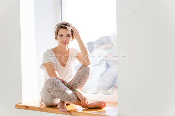Sevimli genç kadın pijama oturma pencere eşiği kısa Stok fotoğraf © deandrobot