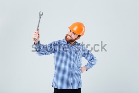 Happy young man builder in hard hat pointing away Stock photo © deandrobot