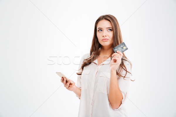 Thoughtful woman holding credit card and using smertphone Stock photo © deandrobot