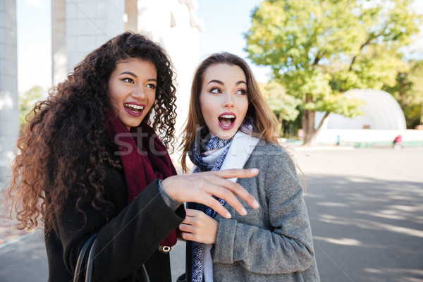 Two surprised young women wearing scarfs communication and look aside Stock photo © deandrobot