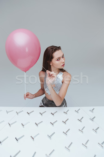 Stock photo: Woman piercing balloon by needle at table with razor blades