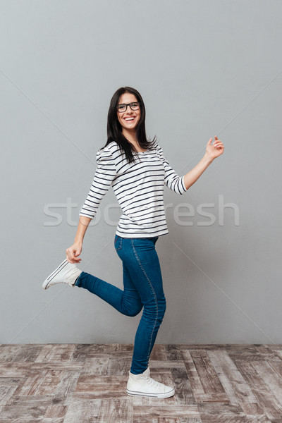 Playful young woman posing over grey background Stock photo © deandrobot
