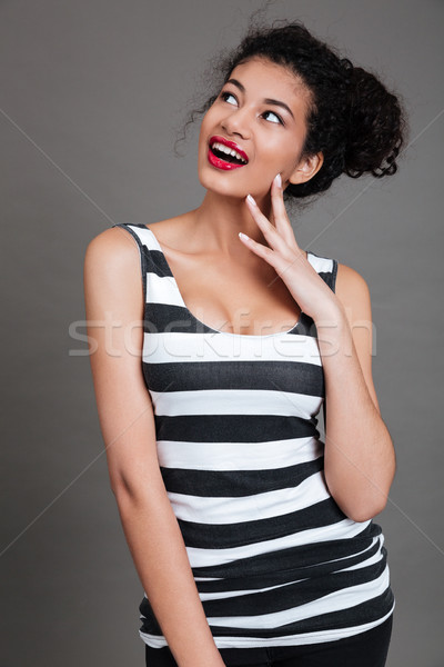 Portrait of a pretty young african woman wondering about something Stock photo © deandrobot